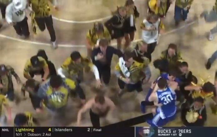 Basketball player collides with fan during court storming, raising safety concerns in collegiate sports.